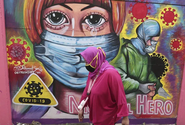 A woman walks past a coronavirus-themed mural honoring health workers in Tangerang, Indonesia, Tuesday, January 26, 2021. Indonesia has reported more cases of the virus than any other countries in Southeast Asia. (Photo by Tatan Syuflana/AP Photo)