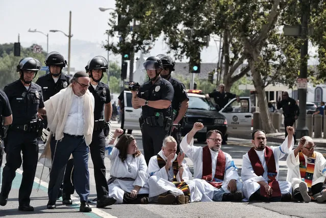 A member of clergy group, left, is arrested during a protest in front of Federal Courthouse in Los Angeles on Tuesday, June 26, 2018. Immigrant-rights advocates asked a federal judge to order the release of parents separated from their children at the border, as demonstrators decrying the Trump administration's immigration crackdown were arrested Tuesday at a rally ahead of a Los Angeles appearance by Attorney General Jeff Sessions. (Photo by Richard Vogel/AP Photo)