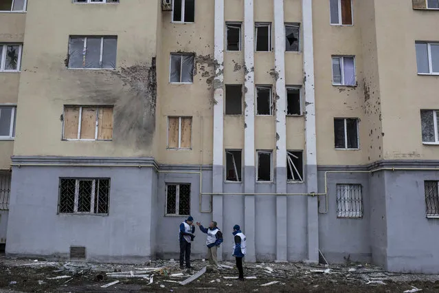 Organization for Security and Co-operation in Europe (OSCE) monitors investigate outside an apartment building damaged in Saturday's shelling in which scores of people were killed and injured in Mariupol, Ukraine, Tuesday, January 27, 2015. European Union leaders are threatening fresh sanctions against Russia because of what it sees as “growing support” of Moscow for separatists in eastern Ukraine during intensified fighting over the past days. (Photo by Evgeniy Maloletka/AP Photo)
