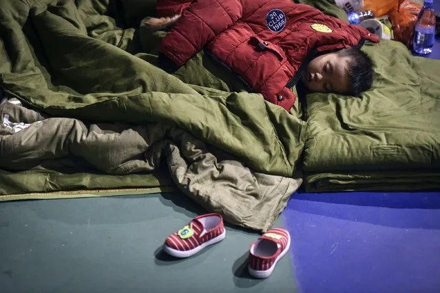 In this photo released by China's Xinhua News Agency, an evacuated boy rests at a makeshift shelter place located at a sports center in Shenzhen, south China's Guangdong Province Monday, December 21, 2015. More than 50 people were missing Monday, a day after a massive landslide buried dozens of buildings when it swept through an industrial park in the southern Chinese city of Shenzhen. (Photo by Mao Siqian/Xinhua via AP Photo)