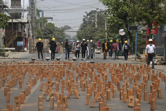 Demonstrators walk near the bricks placed on the road as a roadblock during a protest against the military coup in Mandalay, Myanmar, 10 March 2021. Myanmar security forces on 10 March raided a railway staff compound where railway workers were on strike as part of a civil disobedience movement against the military coup. Anti-coup protests continue in Myanmar amid intensifying violent crackdowns on demonstrators by security forces. (Photo by Kaung Zaw Hein/EPA/EFE)