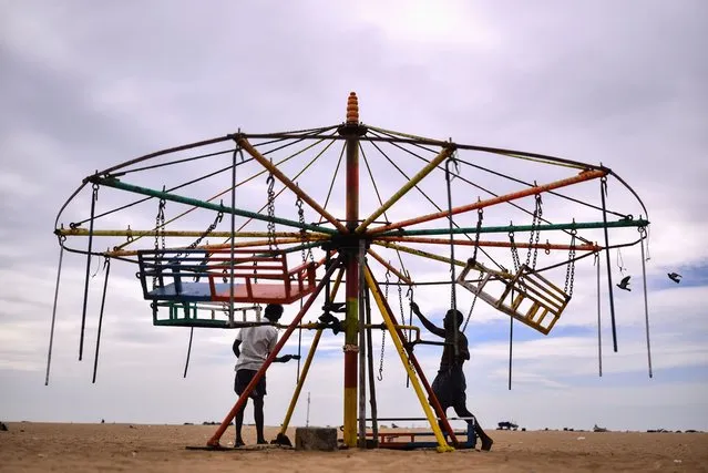 An Indian vendor who offers amusement rides paints a merry-go-round to attract children, during non-business hours, at Marina Beach, in Chennai, India, 05 July 2023.  (Photo by Idrees Mohammed/EPA)
