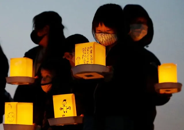 Local residents hold lanterns with messages for earthquake and tsunami victims in Yamada, Iwate prefecture on March 11, 2021, the 10th anniversary of the 9.0-magnitude earthquake which triggered a tsunami and nuclear disaster. (Photo by JIJI Press/AFP Photo)