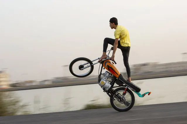 An Iraqi youth shows-off his balancing skills as he performs stunts on a motorbike, on the bank of the Shatt Al-Arab river at sunset, in the southern Iraqi city of Basra, on March 17, 2021. (Photo by Hussein Faleh/AFP Photo)
