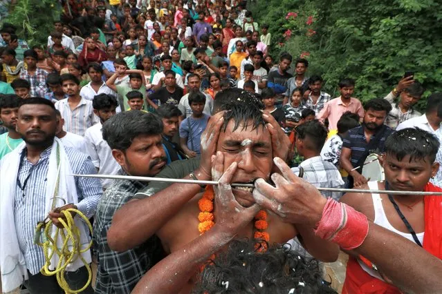A Hindu devotee gets his cheeks pierced as he takes part in an annual religious procession of goddess Sheetla Mata, in Chandigarh on August 13, 2023. (Photo by AFP Photo/Stringer)