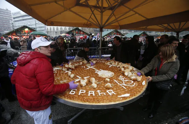 People break traditional Christmas bread to mark the Orthodox Christmas Day festivities in Belgrade, Serbia, Wednesday, January 7, 2016. (Photo by Darko Vojinovic/AP Photo)