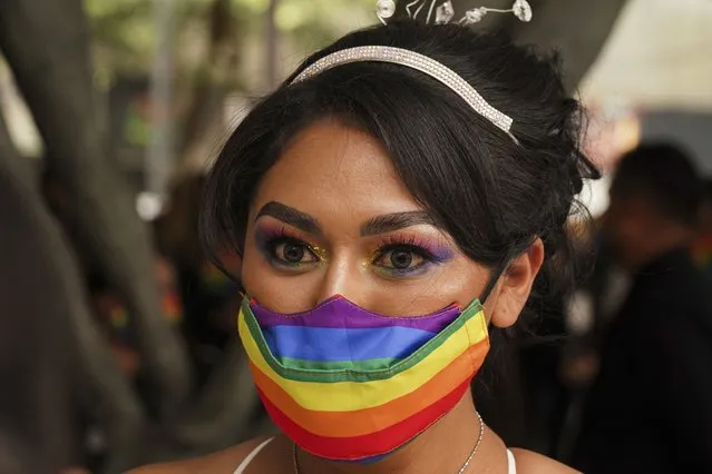 A woman wearing a face mask with the colors of the rainbow listens a judge during a mass wedding ceremony organized by city authorities as part of the LGBT pride month celebrations, in Mexico City, Friday, June 24, 2022. (Photo by Fernando Llano/AP Photo)