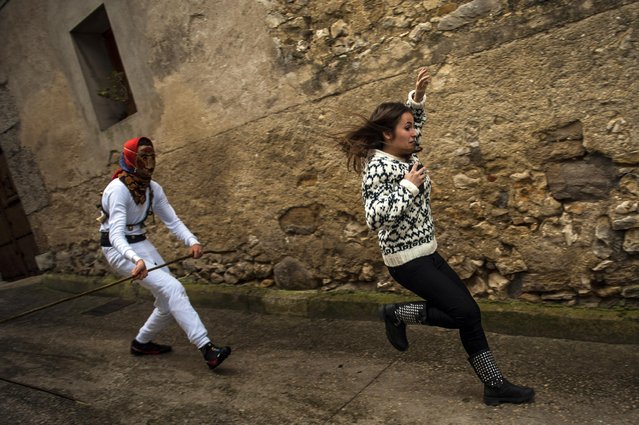 In this photo taken on Sunday, February 15, 2015 a girl runs away from a “Mamuxarro” during the carnival, in the small town of Unanu, northern Spain. While Rio de Janeiro may boast the world’s most famous carnival, the festive period of masquerades and wild and colorful costumes that precedes the Christian religious season of Lent is also a permanent and popular fixture for celebration in Spain and Portugal, with each country having its own strange and unique way of doing it. (Photo by Alvaro Barrientos/AP Photo)
