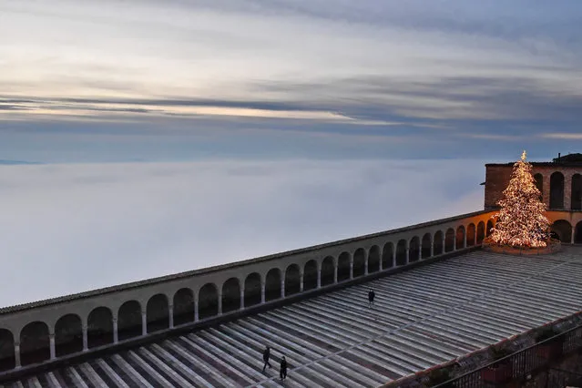This photograph taken on December 11, 2020 shows fog that covers the valley in Assisi as the sun sets. (Photo by Tiziana Fabi/AFP Photo)