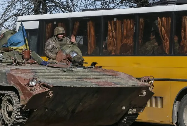 A member of the Ukrainian armed forces welcomes his comrades who fought in Debaltseve, as they sit in a bus while preparing to return home, in Artemivsk, eastern Ukraine, February 24, 2015. Pro-Russia separatists said on Tuesday they began withdrawing heavy weapons from the frontline in east Ukraine under a ceasefire deal, but the Ukrainian military, which says it won't pull back until fighting stops, reported further shelling.  REUTERS/Gleb Garanich  (UKRAINE - Tags: POLITICS MILITARY CONFLICT CIVIL UNREST)