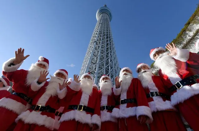 Santa Clauses pose underneath the landmark Tokyo Sky Tree in Tokyo on December 10, 2016. The Japan Toy Association, consisting of 211 toy companies, held the Christmas event to attract toy as gift on the Christmas day. (Photo by Toshifumi Kitamura/AFP Photo)