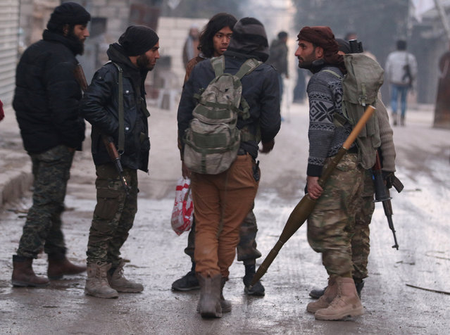 Rebel fighters carry their weapons in a rebel-held area of Aleppo, Syria December 8, 2016. (Photo by Abdalrhman Ismail/Reuters)