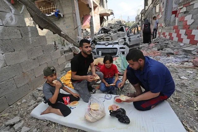 A Palestinian family eat meal near their destroyed house after “mutual and simultaneous” cease-fire deal between Israel and Hamas reached with Egypt mediation took effect at 2 a.m. Friday (2300GMT Thursday), ending the 11-day conflict in Beit Hanoun, Gaza on May 21, 2021. (Photo by Ashraf Amra/Anadolu Agency via Getty Images)