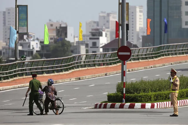 A Vietnamese policeman, left, leads a local woman crossing a blocked street in Danang, Vietnam, Friday, November 10, 2017, ahead of the arrival of U.S. President Donald Trump to attend the Asia-Pacific Economic Cooperation (APEC) Summit. (Photo by Na Son Nguyen/AP Photo)
