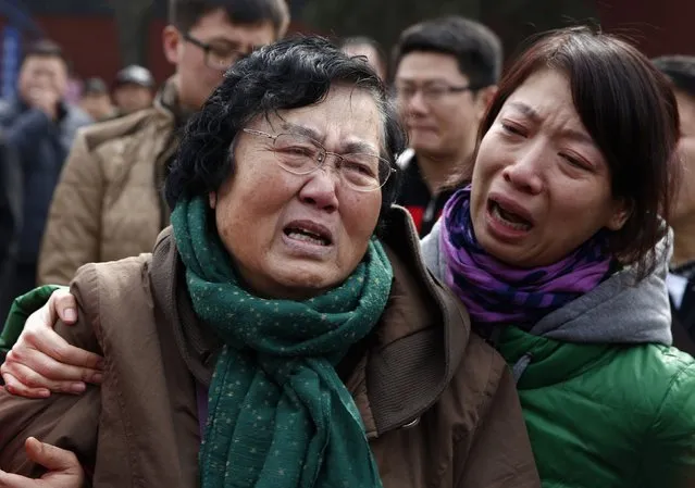 Wang Guohui (L), mother of Li Zhi, a passenger of the missing Malaysia Airlines flight MH370, cries with daughter-in-law Catherine Gang during a gathering of family members of the missing passengers at Yonghegong Lama Temple in Beijing March 8, 2015. Malaysian and Chinese officials say they are committed to the search for MH370 and in assisting families who are still waiting for concrete information on what happened to their loved ones a year ago.    
REUTERS/Kim Kyung-Hoon
