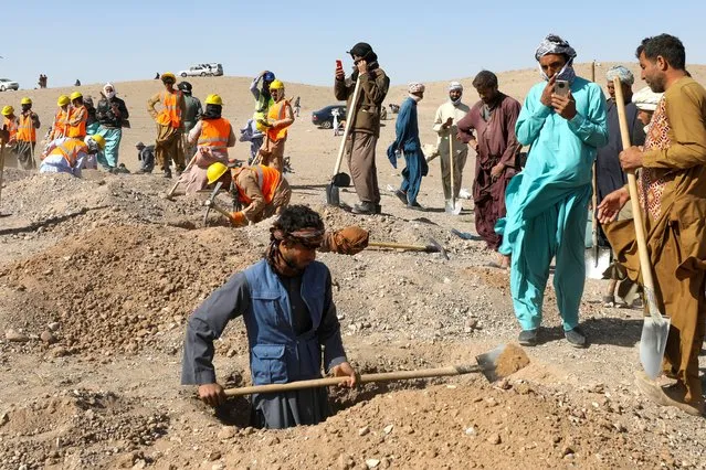 Afghans dig graves for the victims' bodies from the earthquakes in Sarbuland village, Zendeh Jan district of Herat province on October 8, 2023. The death toll from a series of earthquakes in western Afghanistan rose sharply again on October 8 to more than 2,000, with nearly 10,000 injured, as rescue workers dug through razed villages for vanishing signs of life. More than 1,300 homes were toppled when magnitude 6.3 quake – followed by eight strong aftershocks – jolted hard-to-reach areas 30 kilometres (19 miles) northwest of the provincial capital of Herat, according to officials. (Photo by Mohsen Karimi/AFP Photo)