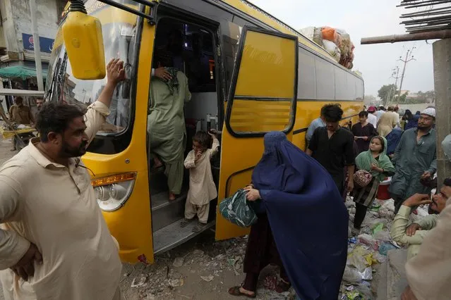 Afghan families board into a bus to depart for their homeland, in Karachi, Pakistan, Friday, October 6, 2023. (Photo by Fareed Khan/AP Photo)