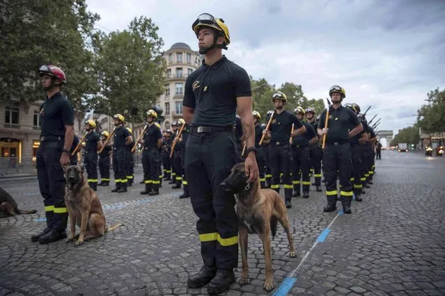 Paris firefighters and their military dogs await on the Champs Elysees avenue during a rehearsal for the Bastille Day parade in Paris Monday, July 12, 2021. Bastille Day is the French national holiday that commemorates the beginning of the French Revolution on July 14, 1789. (Photo by Lewis Joly/AP Photo)