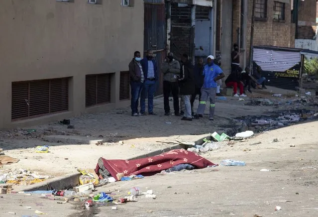 A body is covered by a blanket in Johannesburg, Sunday, July 11, 2021. (Photo by Yeshiel Panchia/AP Photo)