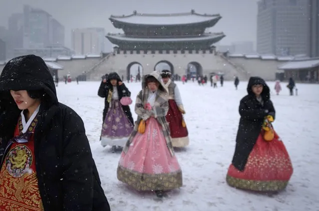 Visitors wearing traditional hanbok dress walk through Gyeongbokgung palace during snowfall in central Seoul on December 13, 2018. (Photo by Ed Jones/AFP Photo)