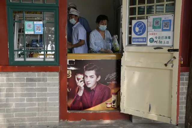 Food vendors work behind an ice cream fridge with an advertisement featuring Chinese-Canadian pop star Kris Wu in Beijing on Tuesday, August 3, 2021. Wu was arrested Monday, Aug. 16, 2021 on suspicion of rape in a high-profile case that followed accusations the singer had s*x with a 17-year-old while she was drunk and lured young women into sexual relationships. (Photo by Ng Han Guan/AP Photo)