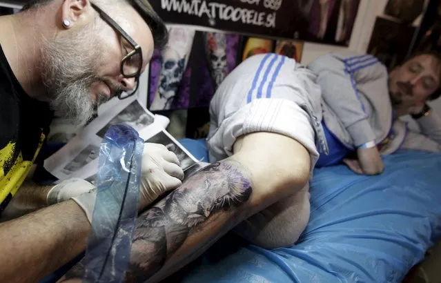 An artist draws a tattoo on a man's leg during a tattoo convention in Ljubljana April 18, 2015. (Photo by Srdjan Zivulovic/Reuters)
