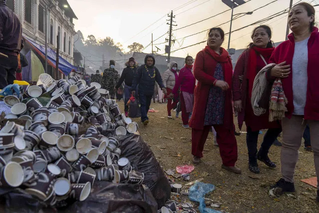 Used tea cups are discarded by the road side as devotees walk during Bala Chaturdashi festival at the Pashupatinath temple premises in Kathmandu, Nepal, Monday, December 11, 2023. Bala Chaturdashi is celebrated in memory of departed family members by lighting oil lamps and scattering seven types of grains along a prescribed route. (Photo by Niranjan Shrestha/AP Photo)