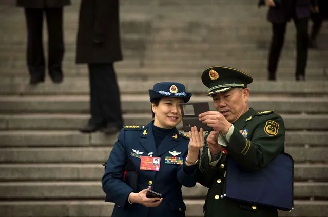 Delegates from the Chinese People's Liberation Army (PLA) take a selfie photo of themselves outside the Great Hall of the People in Beijing, Friday, March 4, 2016. China said Friday it will boost military spending by about 7 to 8 percent this year, the smallest increase in six years, reflecting slowing economic growth and a drawdown of 300,000 troops as Beijing seeks to build a more streamlined, modern military. (Photo by Mark Schiefelbein/AP Photo)