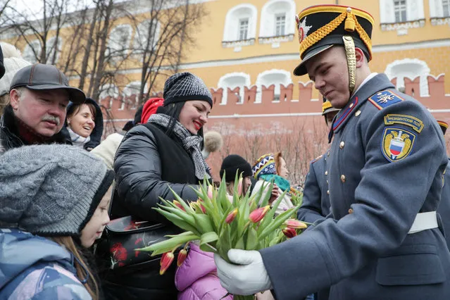 A serviceman of the Presidential Regiment gives flowers to women after performing in the Alexander Garden by the Kremlin wall in Moscow, Russia on March 8, 2019. (Photo by Vyacheslav Prokofyev/TASS)