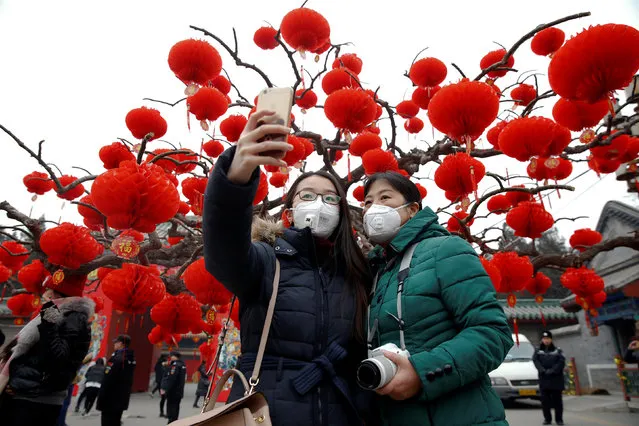 Visitors wearing face masks against pollution take pictures of themselves at the temple fair at Ditan Park (the Temple of Earth) as the Lunar New Year of the Rooster is celebrated, in Beijing, China January 28, 2017. (Photo by Damir Sagolj/Reuters)
