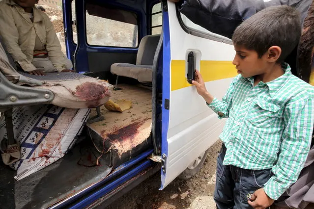 A boy looks at the bloodstains on a vehicle which was used to transport victims near the rubble of houses destroyed by an air strike in the Okash village near Sanaa, April 4, 2015. (Photo by Mohamed al-Sayaghi/Reuters)