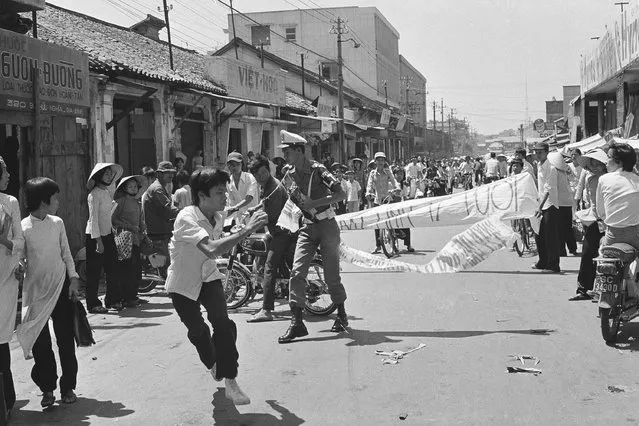 A Saigon student demonstrator hastily flees after a policeman grabbed his antigovernment banner, Thursday, April 9, 1975. About 30 students protested the draft and demanded the ouster of South Vietnamese President Nguyen Van Thieu. (Photo by Dang Van Phuoc/AP Photo)