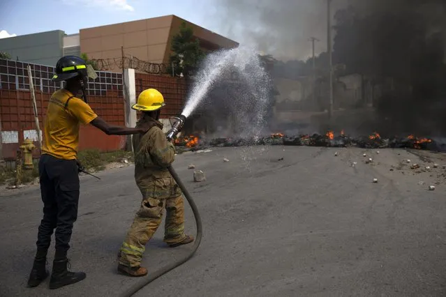 Firefighters douse water on a burning roadblock set by protesters in Port-au-Prince, Haiti, Monday, October 18, 2021. (Photo by Joseph Odelyn/AP Photo)
