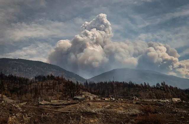 Properties destroyed by the Lytton Creek wildfire on June 30 are seen as a pyrocumulus cloud, also known as a fire cloud, produced by the same fire rises in the mountains above Lytton, British Columbia, on Sunday, August 15, 2021. (Photo by Darryl Dyck/The Canadian Press via AP Phpto)