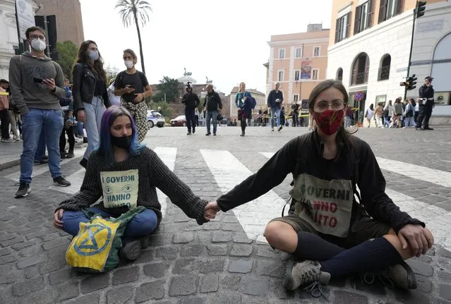 Activists from Extinction Rebellion block a road during a demonstration outside the G20 summit in Rome, Sunday, October 31, 2021. The two-day Group of 20 summit concludes on Sunday, the first in-person gathering of leaders of the world's biggest economies since the COVID-19 pandemic started. Signs on shirts read “Governments have failed”. (Photo by Luca Bruno/AP Photo)