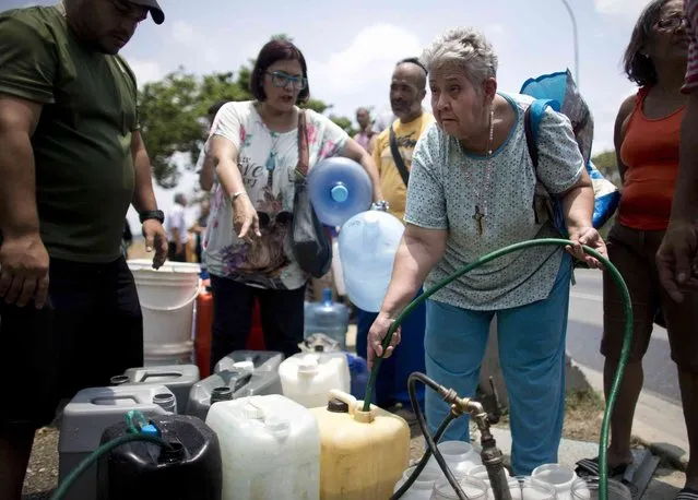 Maria Rojas, 57, fills a container with water from a street tap alongside a highway, in Caracas, Venezuela, Monday, April 1, 2019. Since a massive power failure struck March 7, the nation has experienced near-daily blackouts and a breakdown in critical services such as running water and public transportation. (Photo by Ariana Cubillos/AP Photo)