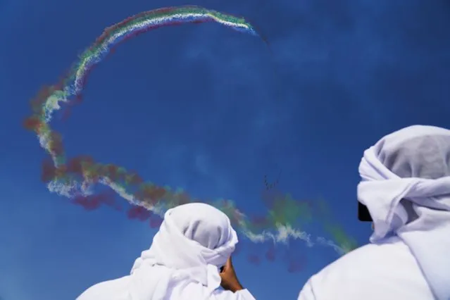 Emiratis watch as Al Fursan, the United Arab Emirates Air Force's aerobatic team, performs at the Dubai Air Show in Dubai, United Arab Emirates, Wednesday, November 17, 2021. (Photo by Jon Gambrell/AP Photo)