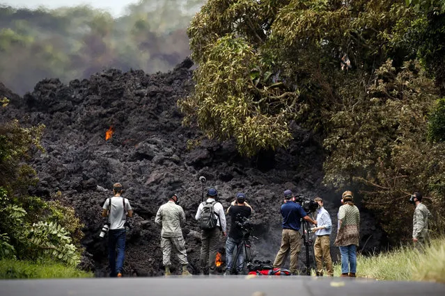 In this May 20, 2018 file photo, members of the media record a wall of lava entering the ocean near Pahoa, Hawaii. It’s been a year since a Hawaii volcano rained lava and gases on a rural swath of the Big Island in one of its largest and most destructive eruptions in recorded history. More than 700 homes were destroyed in the historic eruption, which started May 3 and buried an area more than half the size of Manhattan in now-hardened rock. (Photo by Jae C. Hong/AP Photo/File)