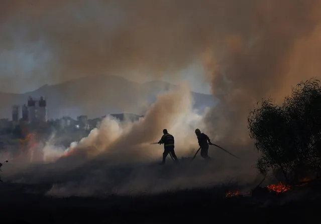 Firefighters work to extinguish a vegetation fire near Hanover Park on the Cape Flats, in Cape Town, South Africa on March 11, 2024. (Photo by Esa Alexander/Reuters)