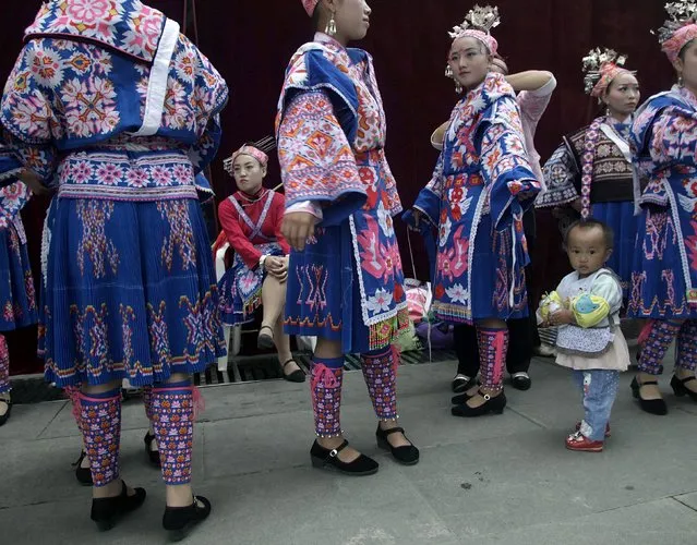 A child looks on as ethnic Miao minority performers in traditional costumes wait backstage before a performance to celebrate an annual festival, in Guiyang, Guizhou province, China, May 25, 2015. (Photo by Reuters/Stringer)
