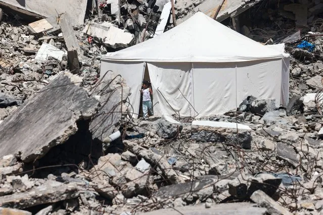 A displaced Palestinian stands at the entrance of a tent set up amid the rubble of a building damaged during Israeli bombardment in Rafah, on the southern Gaza Strip on April 19, 2924, amid ongoing battles between Israel and the militant Hamas group. (Photo by Mohammed Abed/AFP Photo)