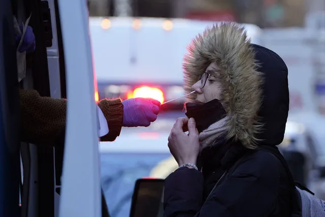 A woman wearing a winter coat gets tested for COVID-19 at a mobile testing site in New York, January 11, 2022. Scientists are seeing signals that COVID-19′s alarming omicron wave may have peaked in Britain and is about to do the same in the U.S., at which point cases may start dropping off dramatically. (Photo by Seth Wenig/AP Photo)
