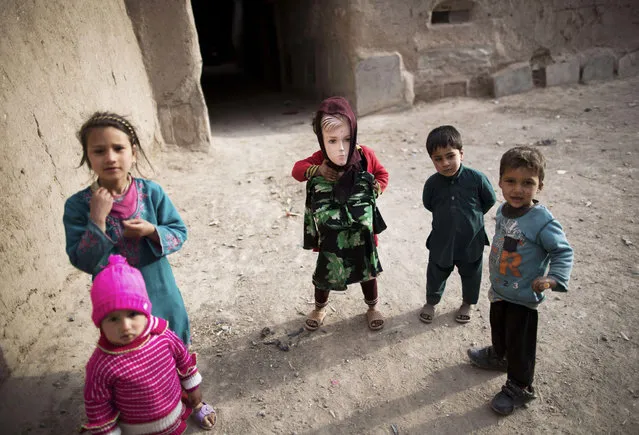 An Afghan girl holds a mannequin as she and her playmates look on in the old part of the northwestern city of Herat on March 31, 2014. Presidential candidates have been holding election rallies across the country for the the upcoming presidential elections on April 5, to choose a successor to President Hamid Karzai, who was barred constitutionally from seeking a third term. (Photo by Behrouz Mehri/AFP Photo)