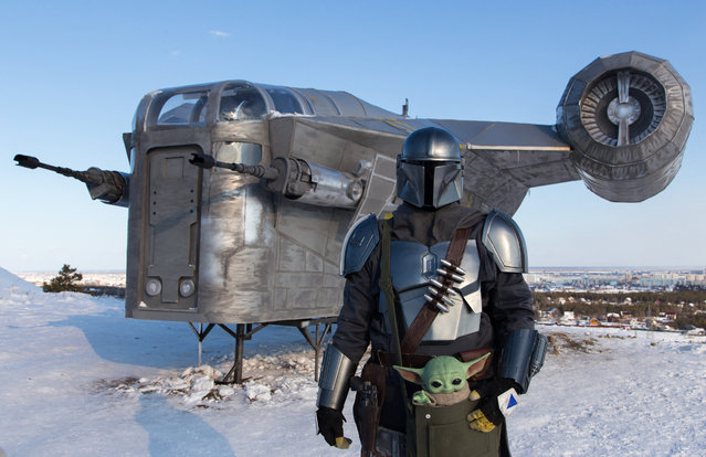 A man wearing a costume of the StarWars protagonist Din Djarin poses in front of a giant replica of the Razor Crest, a gunship from the StarWars spinoff series “The Mandalorian” used by the hit TV show's mysterious bounty hunter to roam the galaxy's outer reaches, in a park of the eastern Siberian city of Yakutsk on March 14, 2021. (Photo by Evgeniy Sofroneyev/AFP Photo)