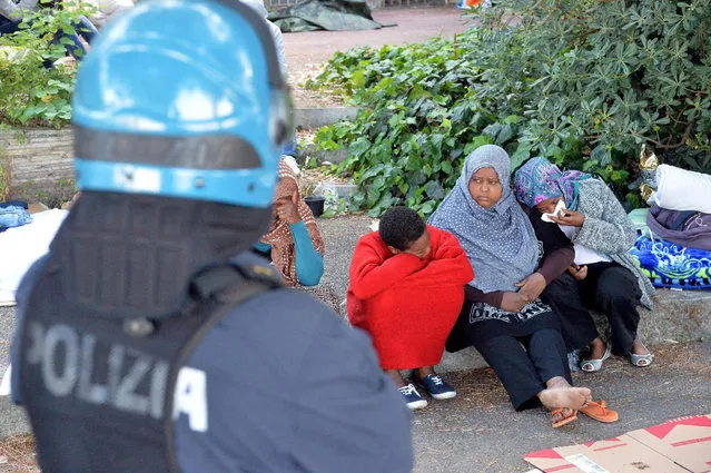 An Italian police officer watches migrants in Ventimiglia, at the Italian-French border Tuesday, June 16, 2015. Police at Italy's Mediterranean border with France have forcibly removed some of the African migrants who have been camping out for days in hopes of continuing their journeys farther north. The migrants, mostly from Sudan and Eritrea, have been camped out for five days after French border police refused to let them cross. (Luca Zennaro/ANSA via AP)