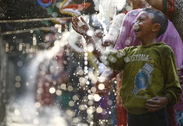 A boy plays with water at the Balaju Baise Dhara (22 water spouts) during the Baishak Asnan festival in Kathmandu, Nepal, April 22, 2016. (Photo by Navesh Chitrakar/Reuters)
