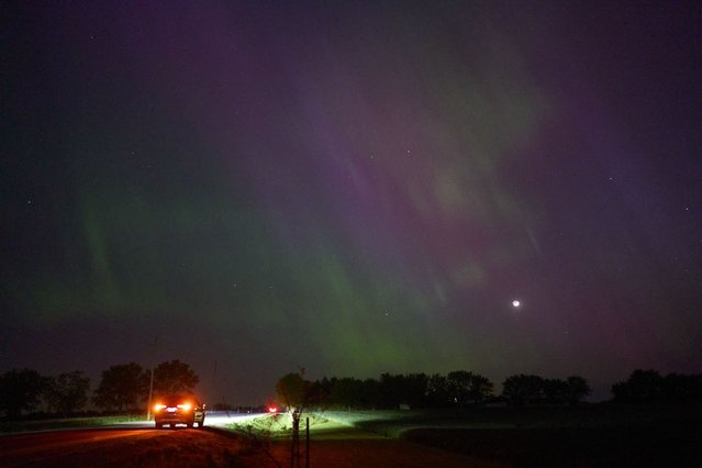 People stop along a country road near London, Ontario to watch the Northern lights or aurora borealis during a geomagnetic storm on May 10, 2024. (Photo by Geoff Robins/AFP Photo)