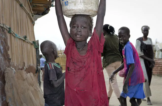 In this photo taken Sunday, December 9, 2018, a young girl carries water on her head in Koythiey displaced person's camp on the outskirts of Bentiu town in South Sudan. Six months ago planning ahead in civil war-torn South Sudan seemed impossible but now, after warring sides signed a new peace deal in September that the government vows will hold, some are starting to rebuild their lives. (Photo by Sam Mednick/AP Photo)