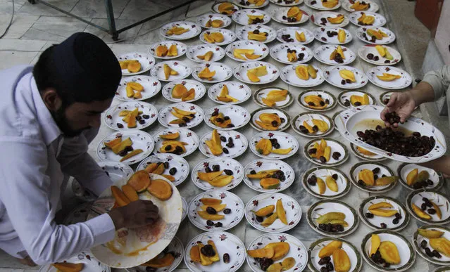 Pakistani volunteers arrange plates for devotees to break the day's fast that many Muslims practice during the month of Ramadan in Lahore, Pakistan, Wednesday, July 1, 2015. Muslims across the world are observing the holy fasting month of Ramadan, where they refrain from eating, drinking and smoking from dawn to dusk. (Photo by K. M. Chaudary/AP Photo)
