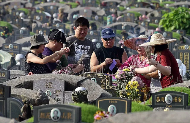 Family members visit the tomb of their loved ones to pay their respects and burn offerings at the Choa Chu Kang Chinese Cemetery during the Qing Ming Festival on April 4, 2013 in Singapore. Qing Ming, also known as Tomb-Sweeping Day, is an annual Chinese festival to commemorate the dead. Families mark the day by visiting and cleaning the graves of their ancestors, burning incense and paper money and presenting offerings such as food, tea, wine and joss paper accessories. (Photo by Suhaimi Abdullah/Getty Images)